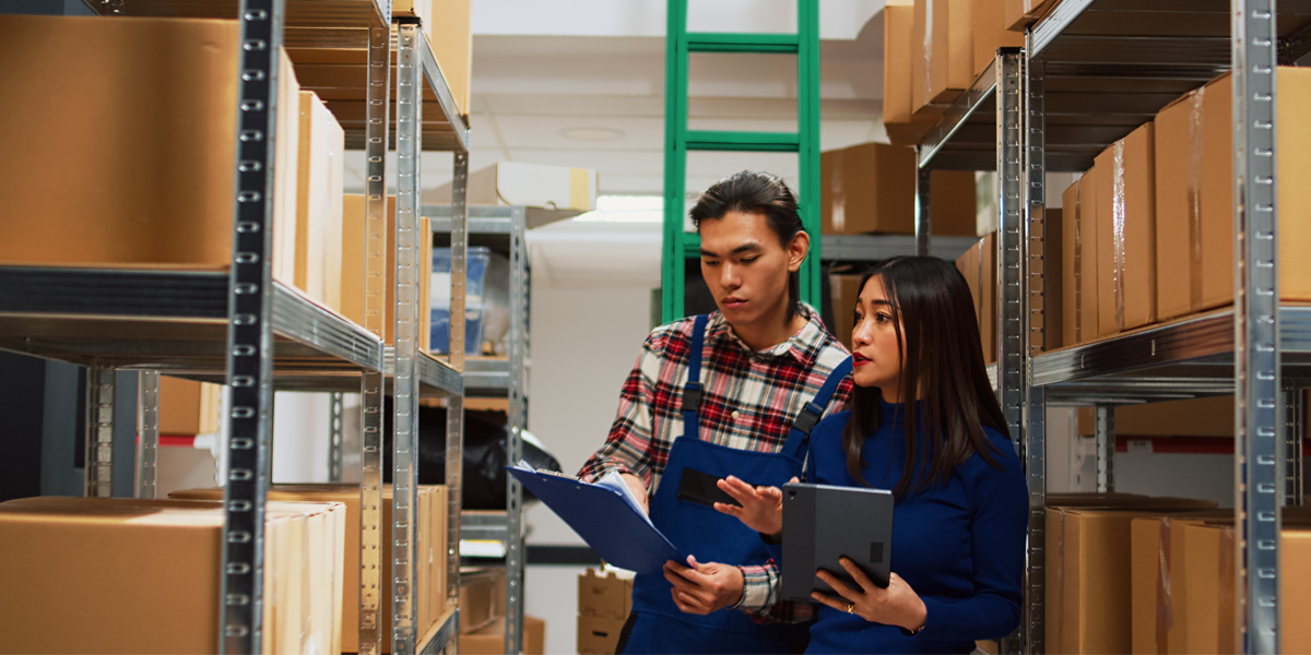 man and woman working in a storage unit looking at boxes and clipboard
