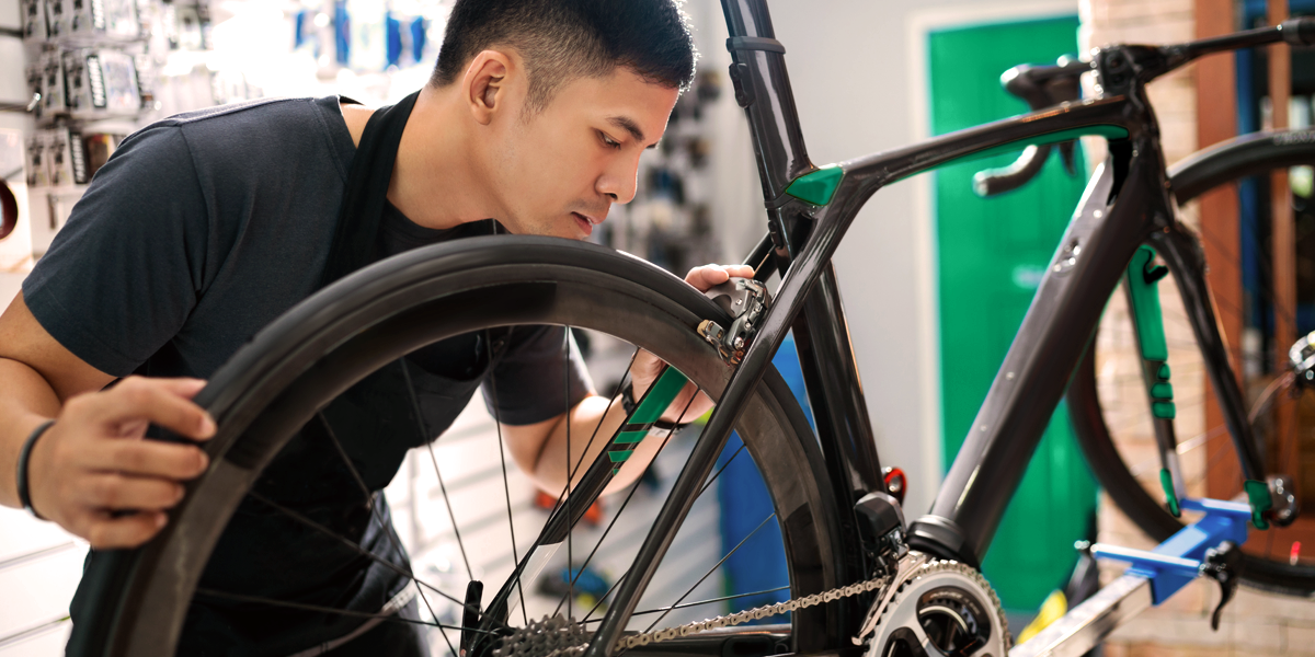 man working on a bicycle doing repairs in a shop