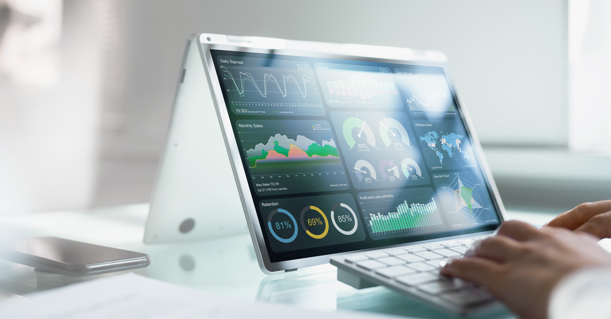 A person typing on a keyboard in front of a computer display showcases various colorful data visualizations, including graphs and charts. In a bright, modern office, they leverage valuable supply chain predictive analytics to guide financial leaders in strategic decision-making.