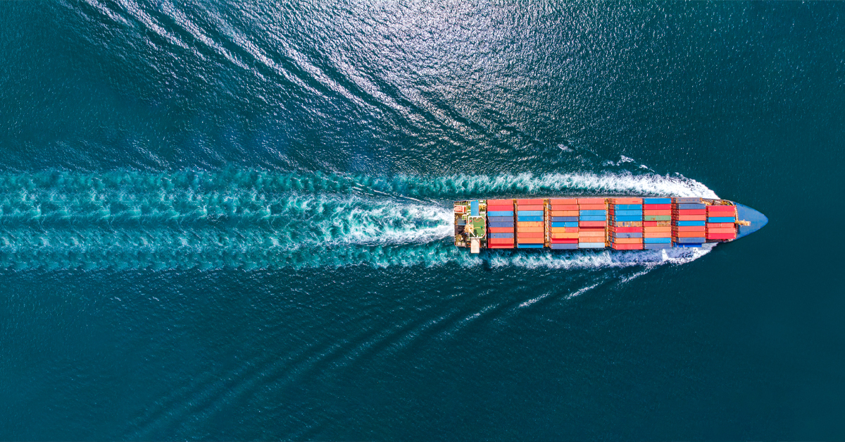 Aerial view of a massive Maersk cargo ship navigating the deep blue ocean, leaving a trail of white waves. This logistics giant is laden with multicolored shipping containers, exemplifying the peak of digital procurement efficiency in global trade.